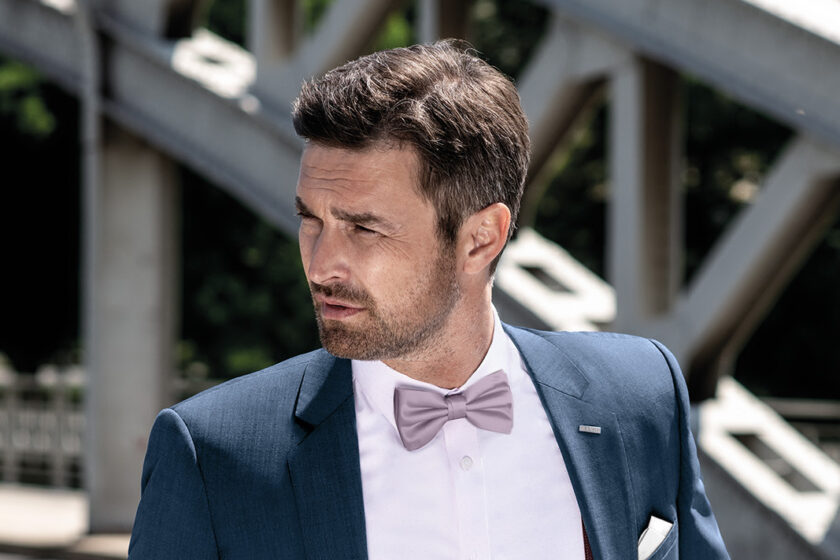 Pánský oblek BANDI Pescaro v netradiční kombinaci s košilí BELLORI Bianco, motýlkem GALLA 20 Polvere, kapešníčkem GALLA 01 oživené o stylové pánské šle EXCLUSIVE 17